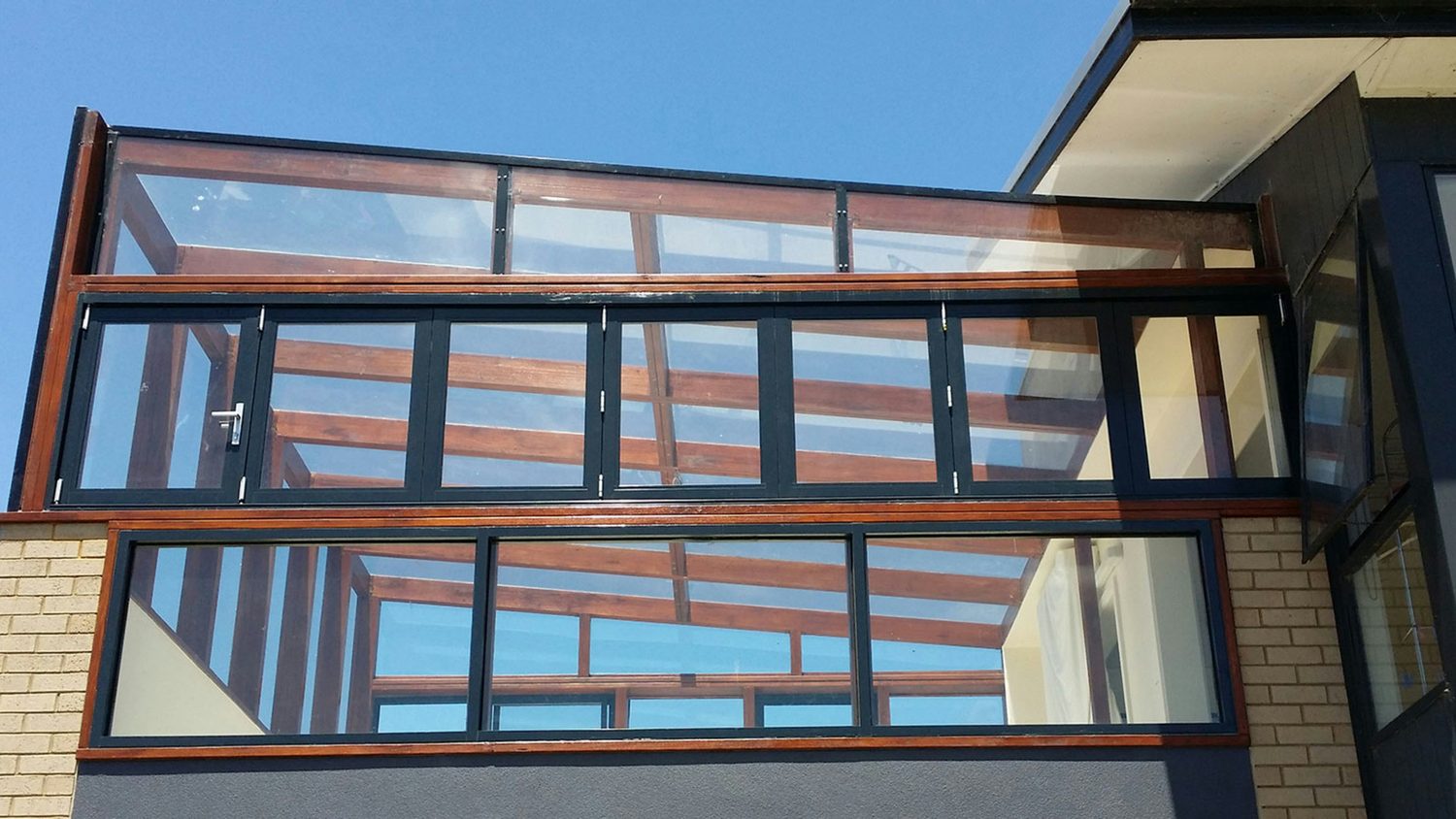 Timber-framed glazed extension against a blue sky
